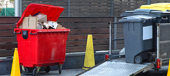 red 6 yard commercial dumpster between two yellow cones